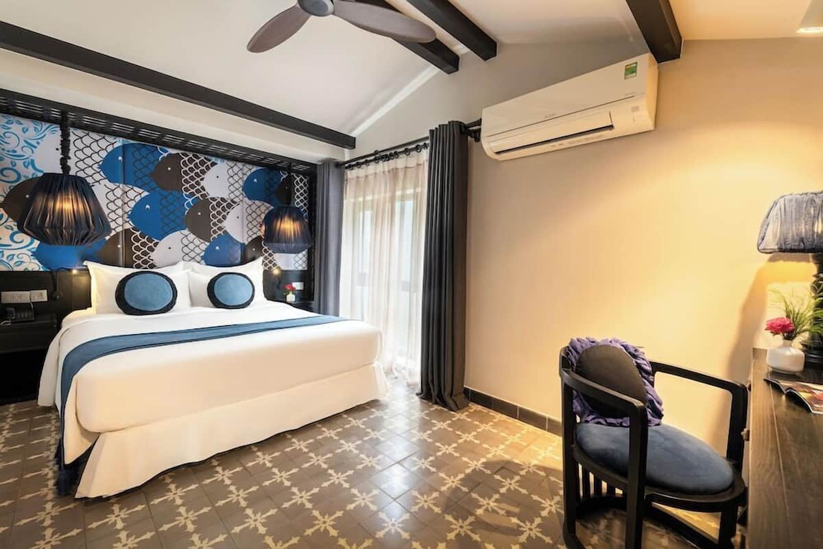Una habitación de hotel con una cama, una silla, un aire acondicionado y una pared con diseño.