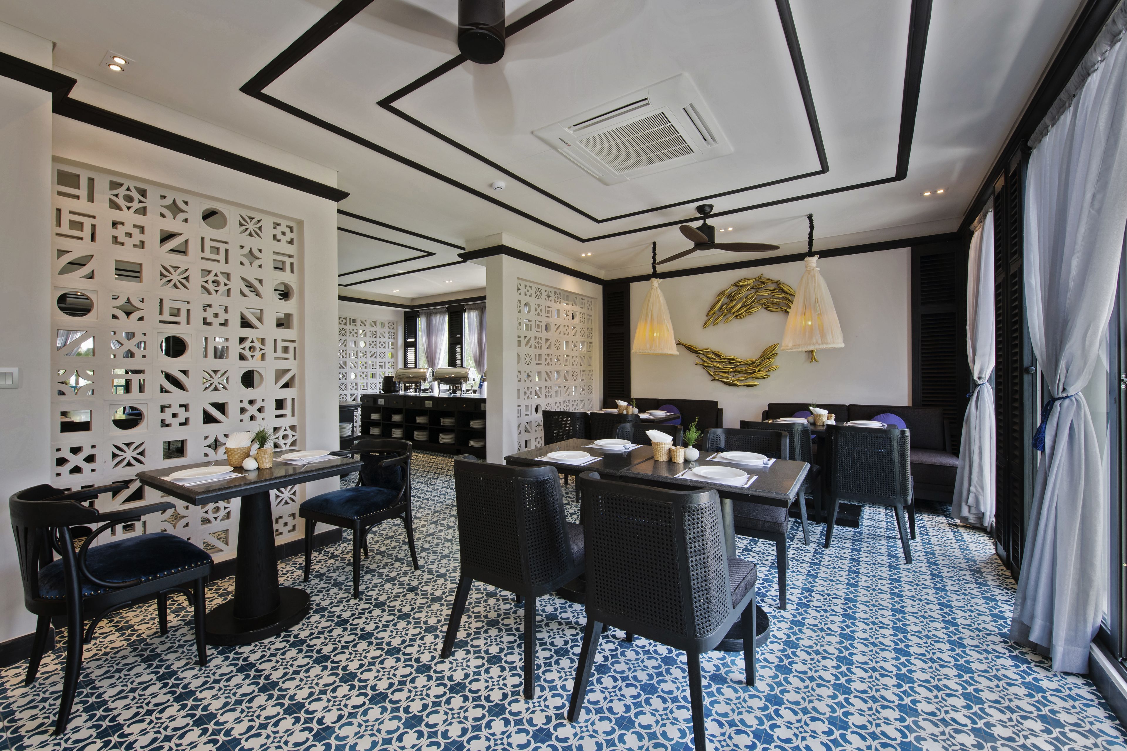 A modern dining area with a geometric ceiling design, patterned floor, and a mix of seating arrangements.