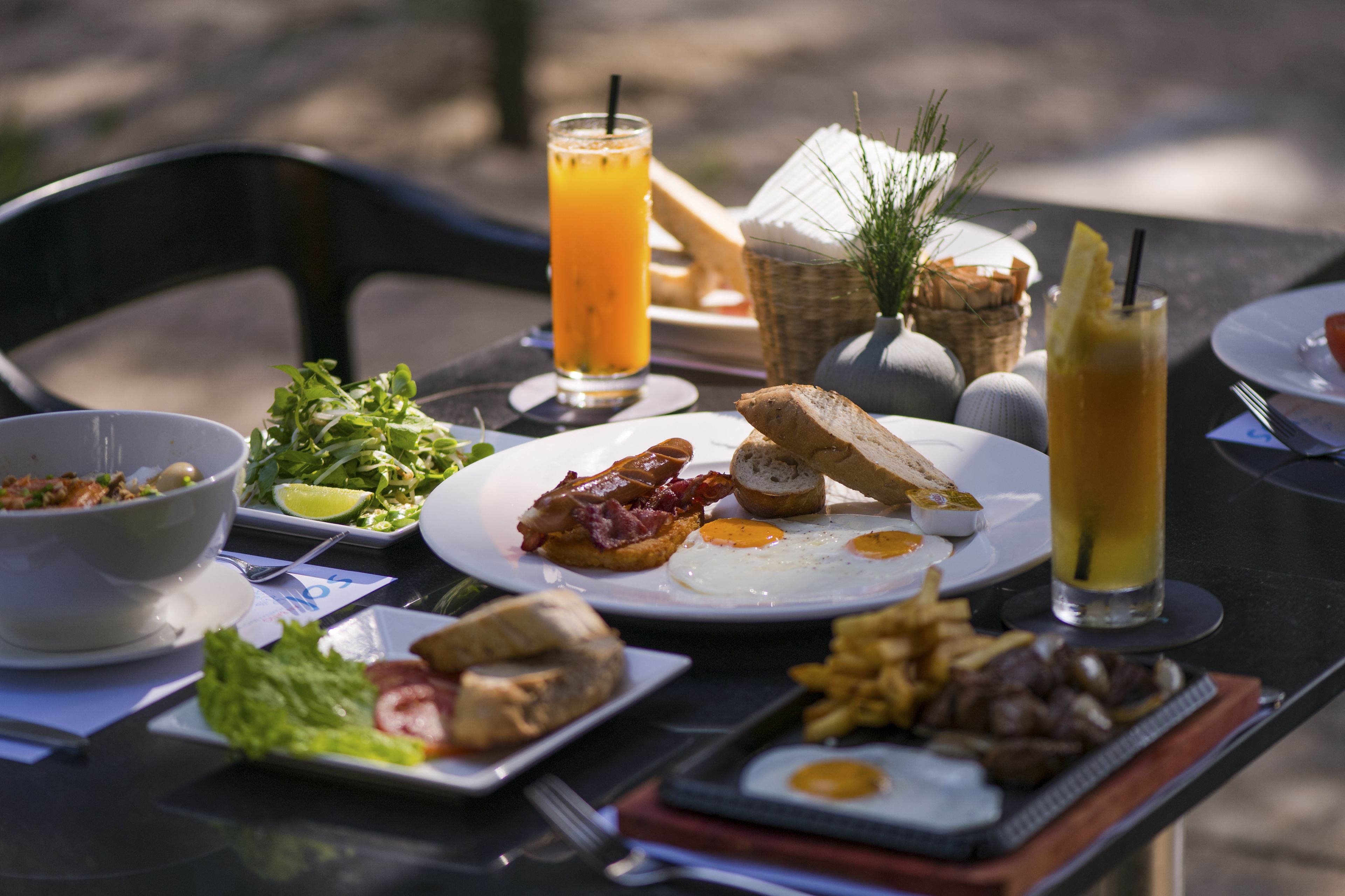 Ett bord dukat med frukostmat, inklusive ägg, bacon, rostat bröd och ett glas apelsinjuice.