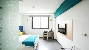 Una habitación de hotel moderna con cama, escritorio, televisor y ventana.