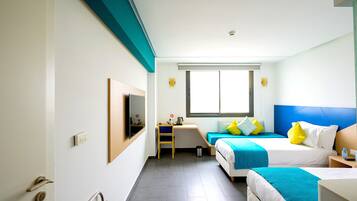 A hotel room with two beds, a desk, a chair, a TV mounted on the wall, and a window.