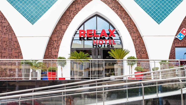 A modern building with a Relax Hotel sign, featuring a geometric facade and a glass entrance.