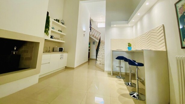 A modern kitchen with white cabinetry, a built-in microwave, and a small island with stools. - B&B Pietramare (Melendugno)
