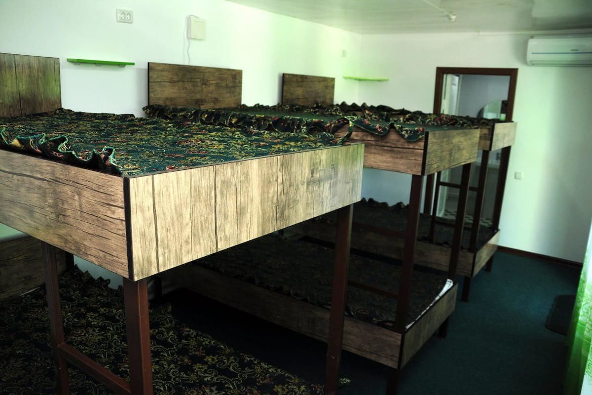 A room with a long wooden table covered with a patterned tablecloth, flanked by wooden benches.