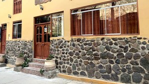 A building with a stone facade, wooden doors, and large windows. - Inka Khawarina Tambo Lodge (Ollantaytambo)