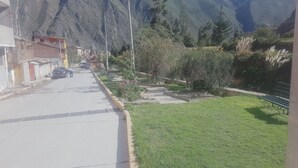 A street with buildings, a parked car, and a grassy area with trees. - Inka Khawarina Tambo Lodge (Ollantaytambo)