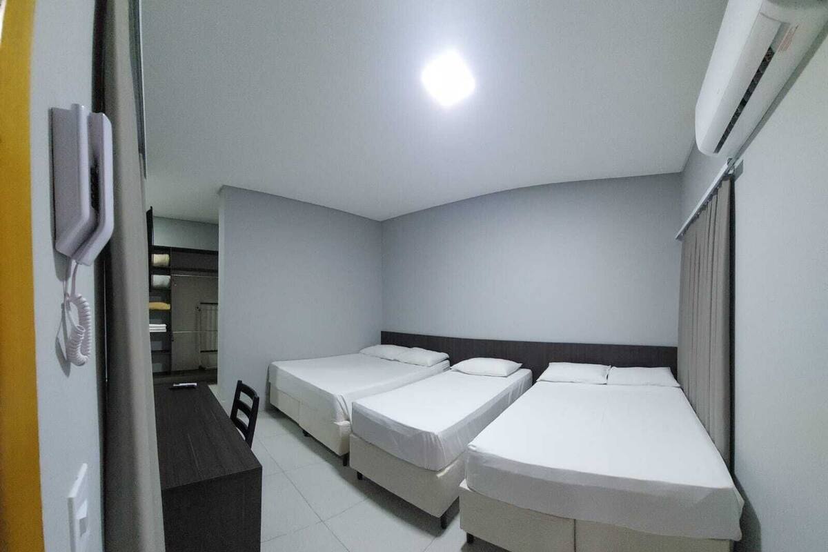 A hotel room with two single beds, a desk, a chair, and a phone on the wall.