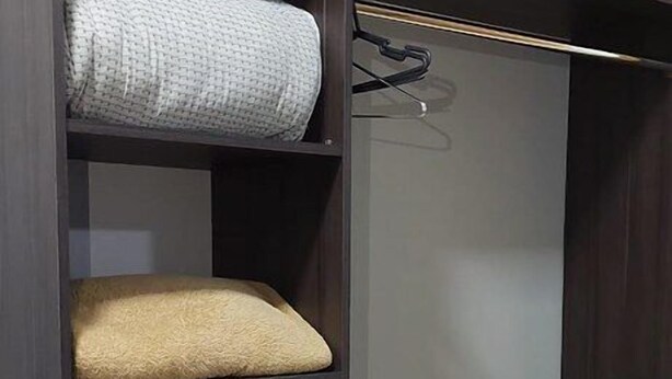 Ein Kleiderschrank mit mehreren Einlegeböden, auf denen gefaltete Handtücher liegen.