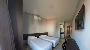 Ein Hotelzimmer mit zwei Einzelbetten, einem Holztisch und einem Spiegel an der Wand.