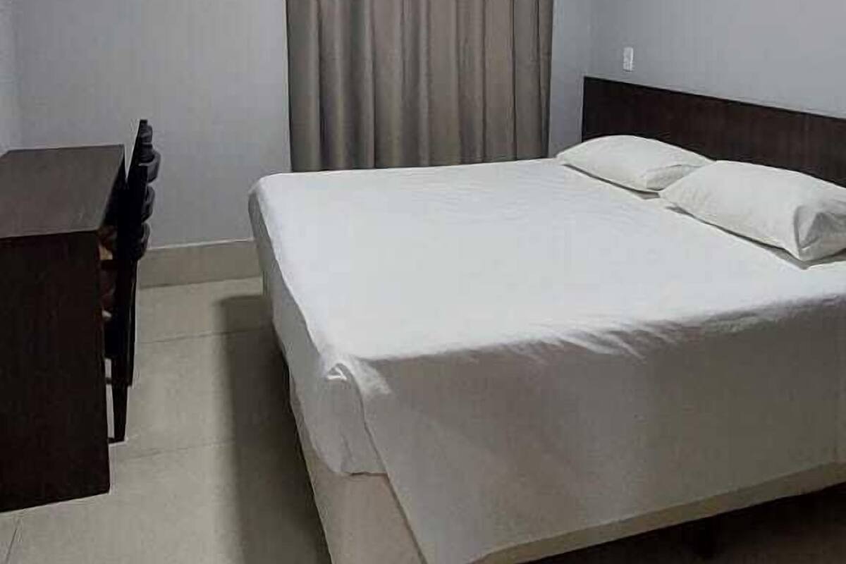 A bedroom with a bed, a desk, and an air conditioning unit.