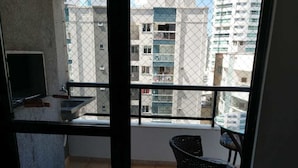 A balcony with a small kitchen area, a chair, and a table. - Apartamento Edifício Dona Anna (Balneário Camboriú)