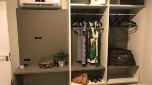 A walk-in closet with hanging clothes, a suitcase, and a handbag. - Apartamento Edifício Dona Anna (Balneário Camboriú)