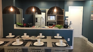 A modern kitchen with a central island, overhead pendant lights, and a microwave. - Apartamento Edifício Dona Anna (Balneário Camboriú)