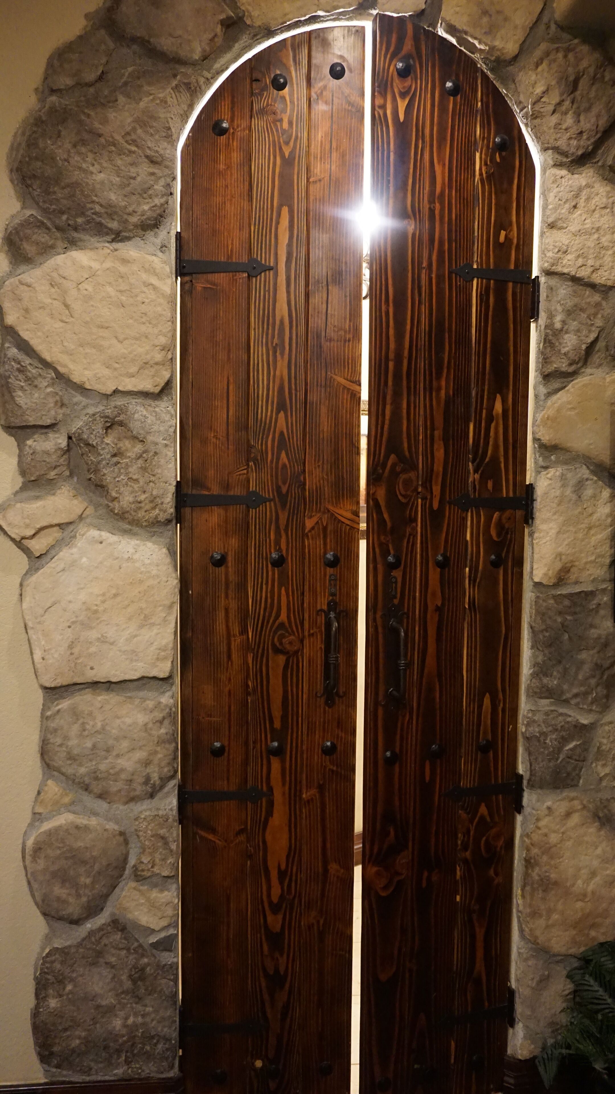 A wooden door with metal hinges and a stone wall background.