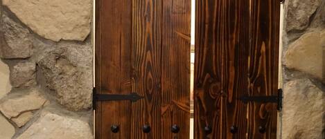 A wooden door with metal hinges and a stone wall background.