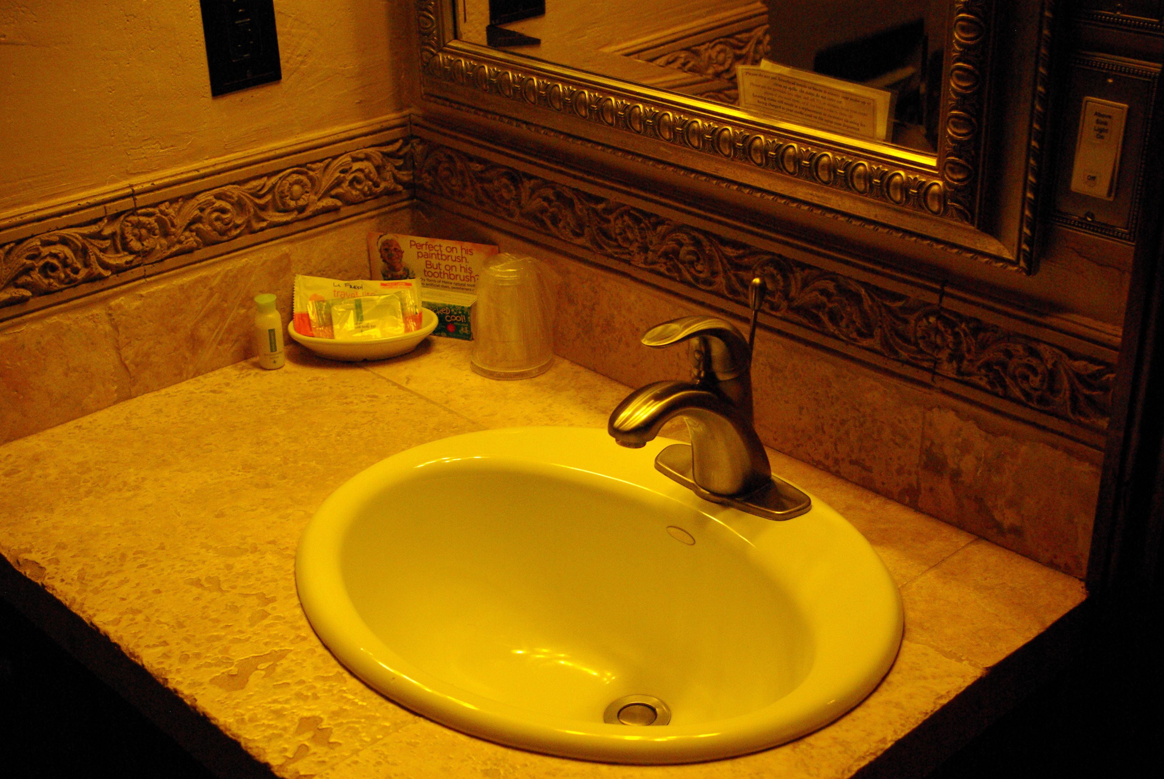 Un lavabo dans la salle de bain, avec un miroir au-dessus, un distributeur de savon et un porte-brosse à dents.