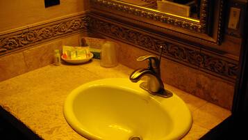 Un lavabo dans la salle de bain, avec un miroir au-dessus, un distributeur de savon et un porte-brosse à dents.