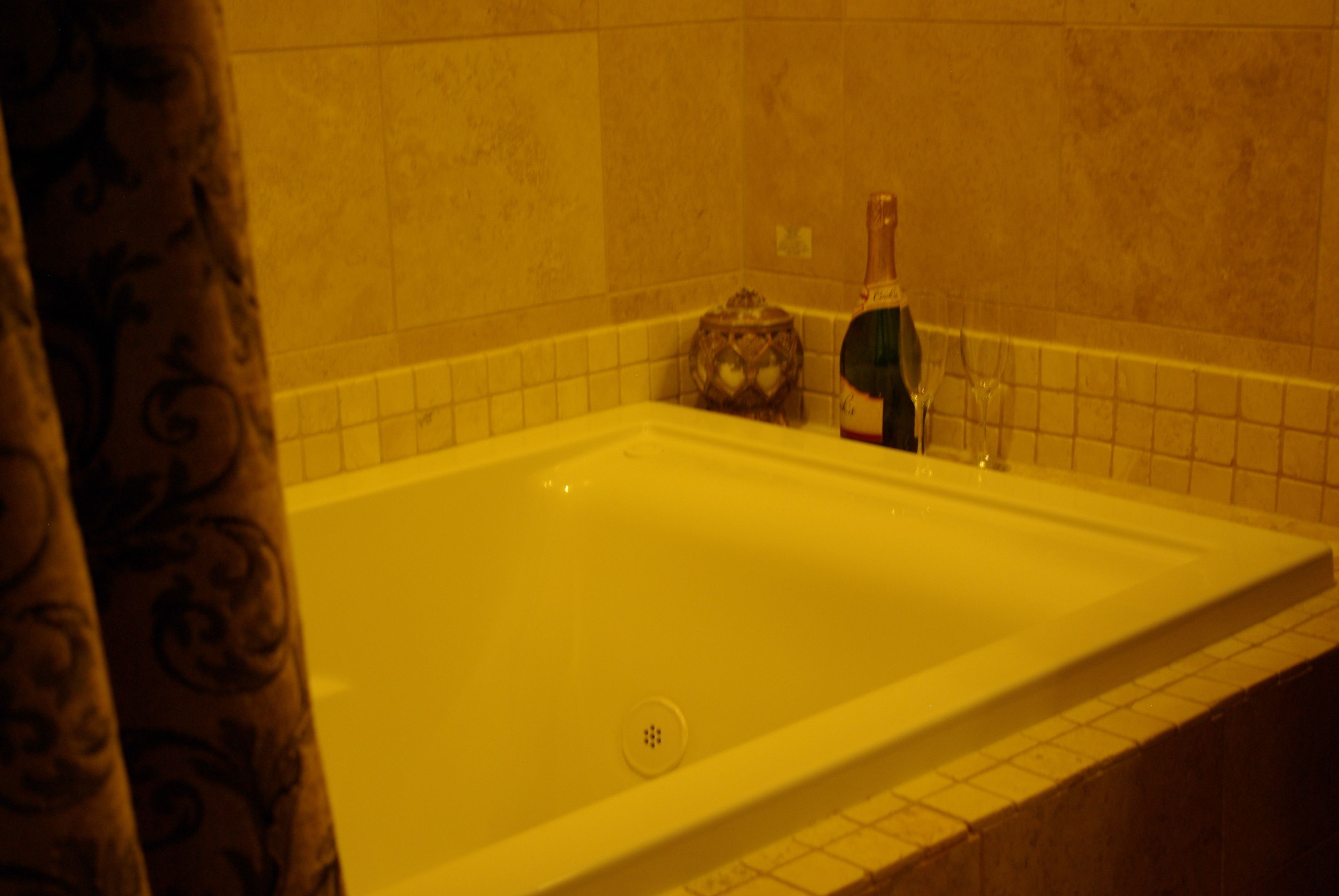 A bathroom with a bathtub, a bottle, and a decorative item on the wall.