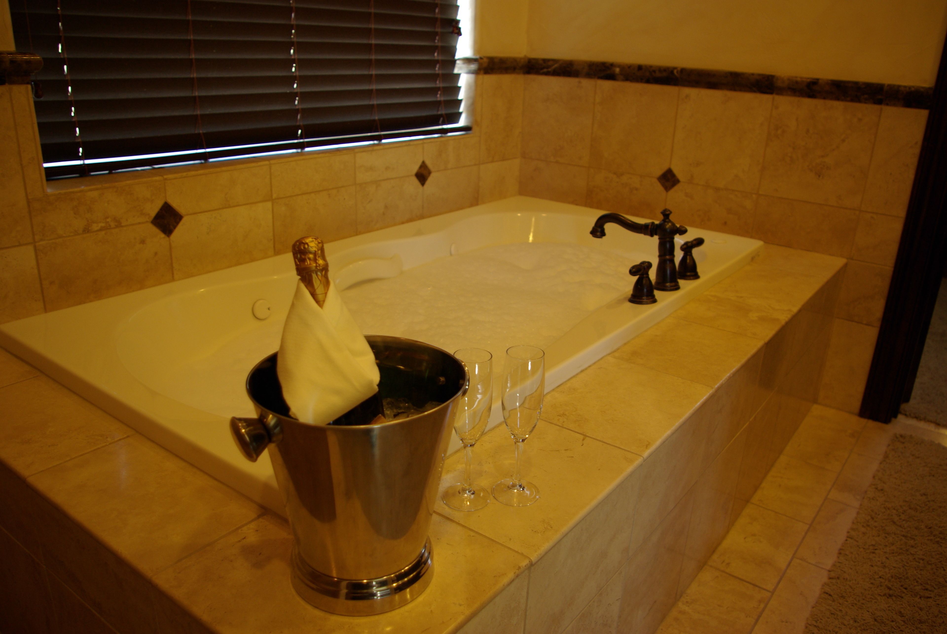 A large bathtub with a champagne bucket and glasses, suggesting a celebration or special occasion.