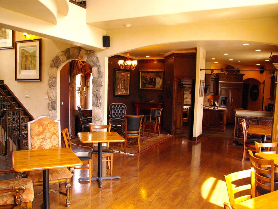 Un comedor amplio con mesas y sillas de madera, un arco de piedra y una escalera que sube a un nivel superior.