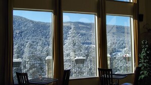 Ein Zimmer mit großen Fenstern und Blick auf eine verschneite Berglandschaft.