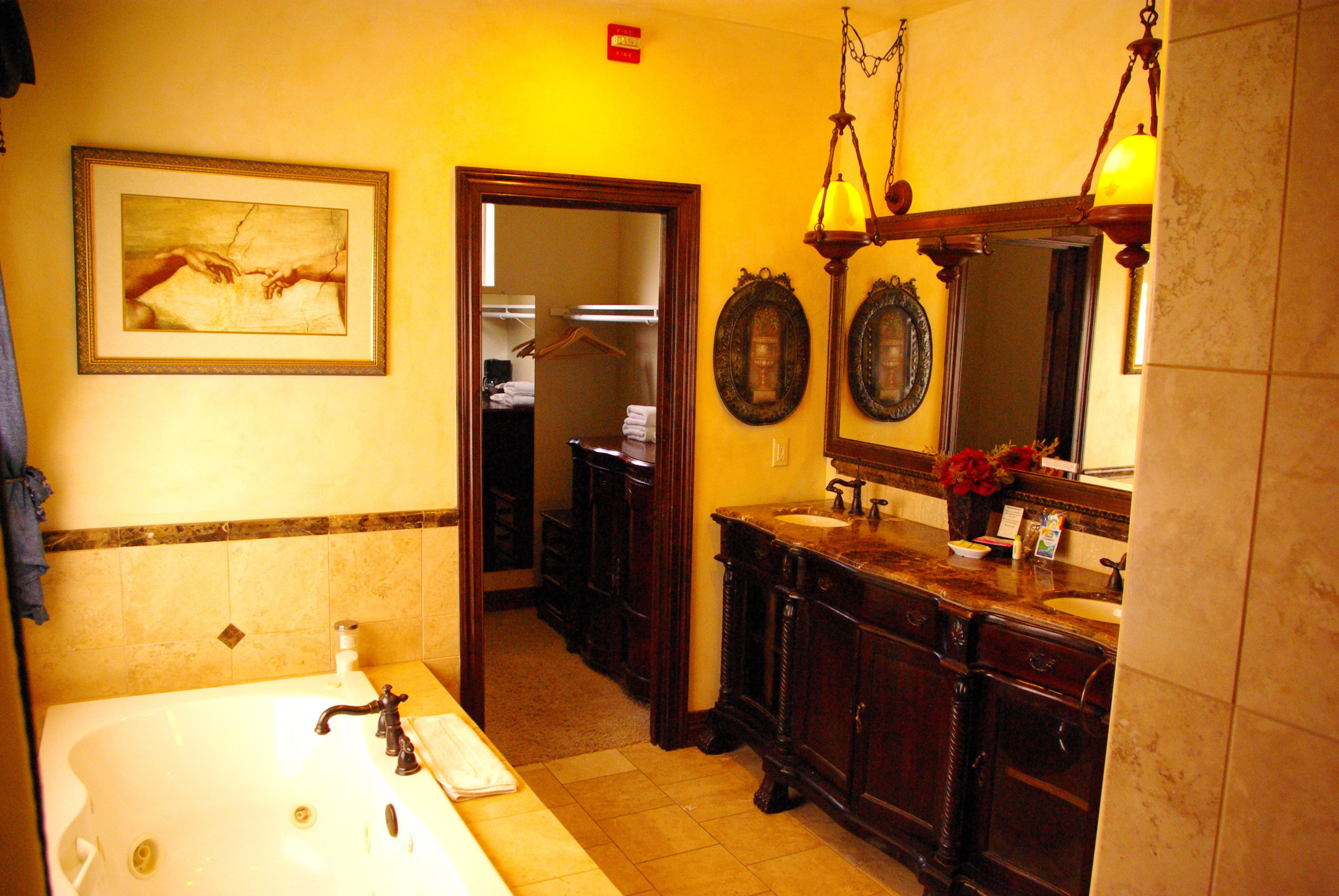 A bathroom with a bathtub, two sinks, a large mirror, and a framed picture on the wall.