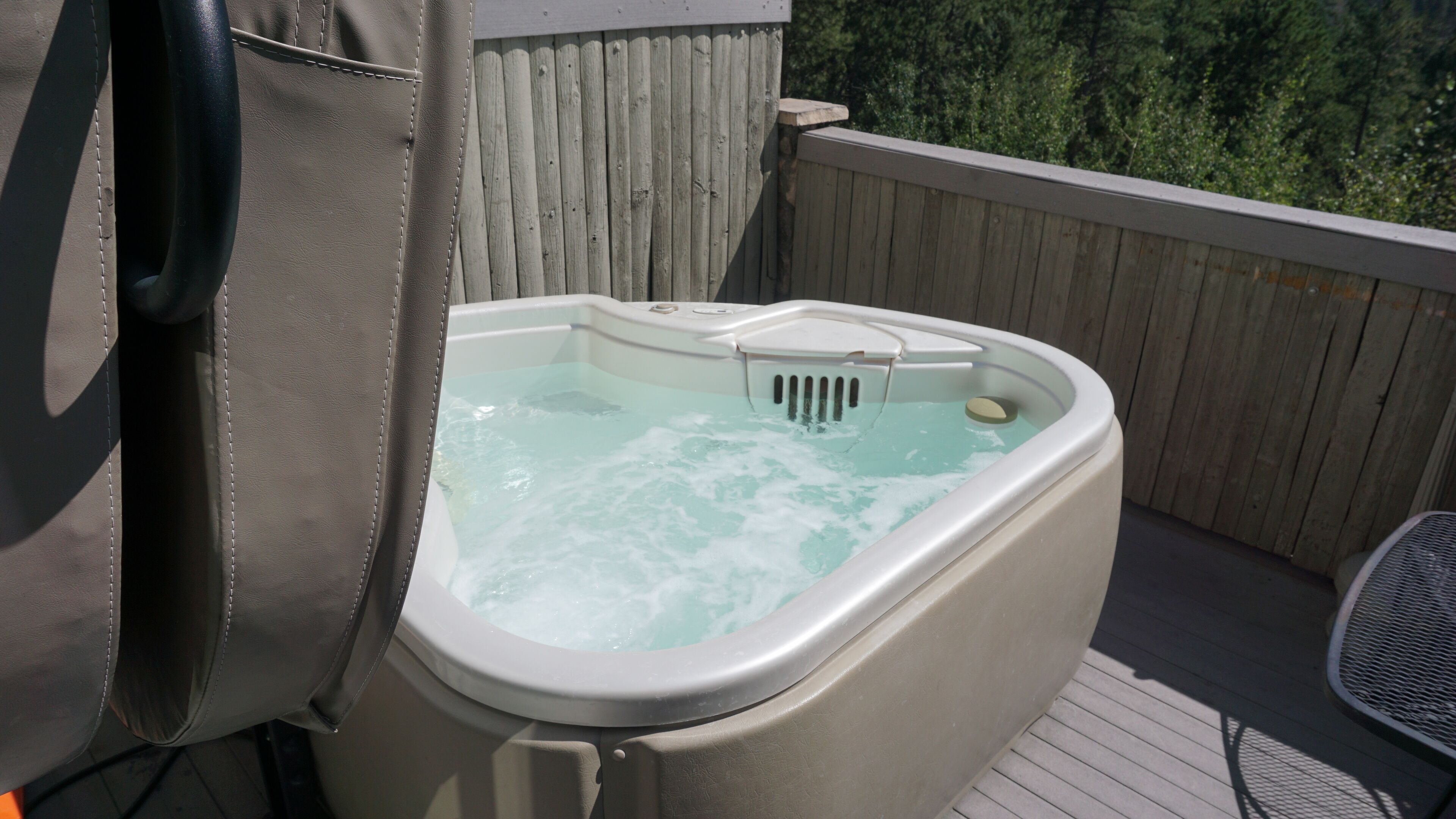 A hot tub on a wooden deck with a view of trees.