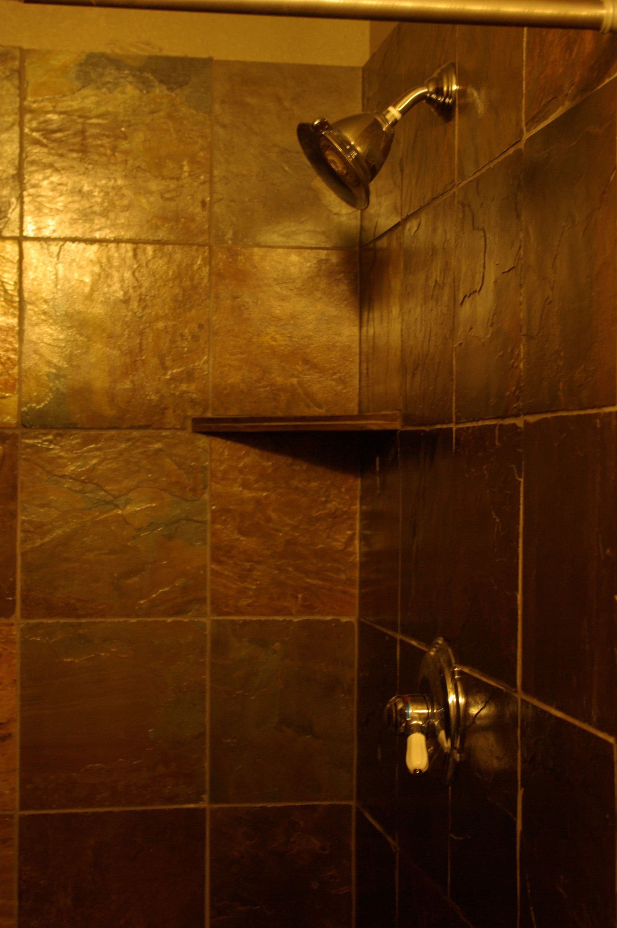 A shower area with a handheld showerhead and a wall-mounted faucet.