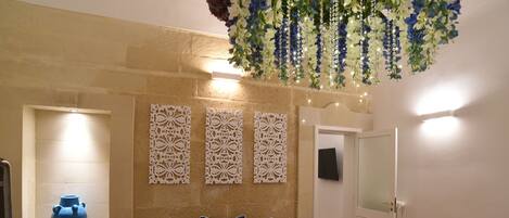Une pièce avec un canapé bleu, des panneaux décoratifs sur les murs, un vase bleu et une composition florale suspendue.