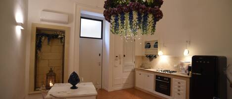 Una cocina moderna con armarios blancos, un refrigerador negro y una araña decorada con flores.