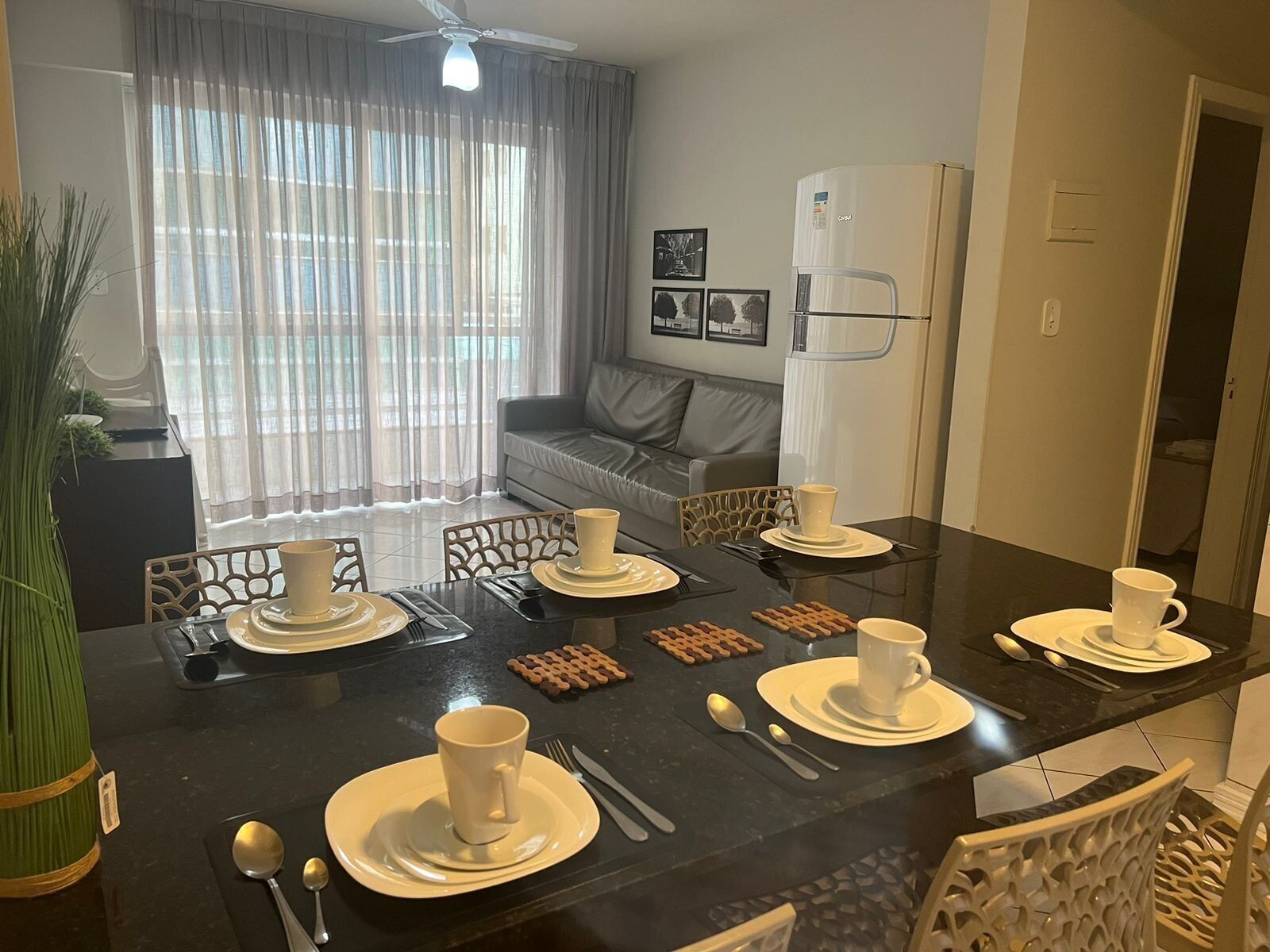 A dining area with a black table set for four, including plates, cups, and cutlery.