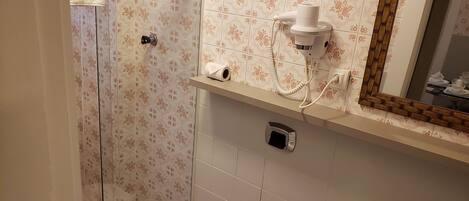 Un baño con ducha, inodoro, lavabo y un espejo con marco decorativo.