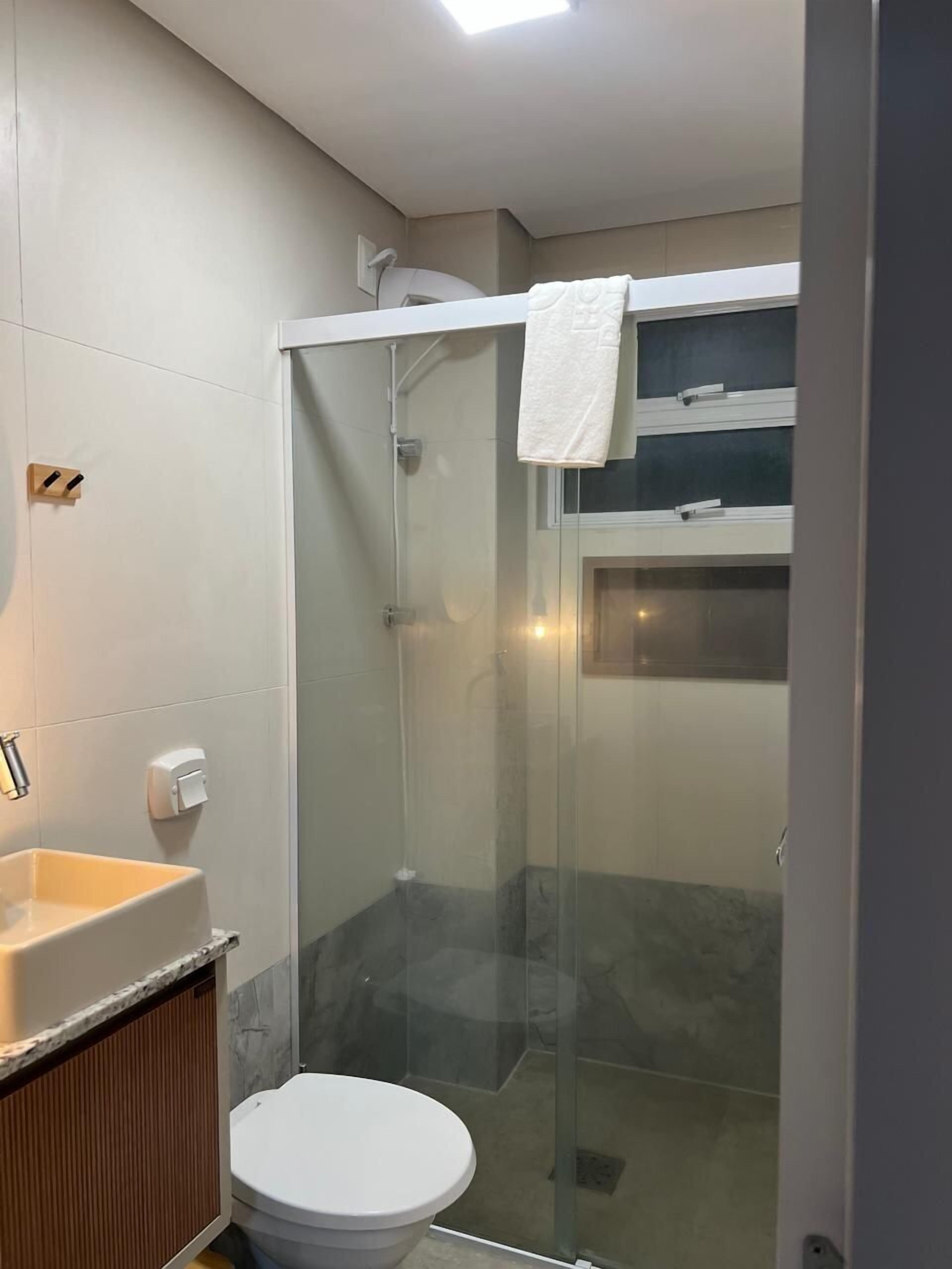 A modern bathroom with a glass-enclosed shower, a toilet, and a sink.
