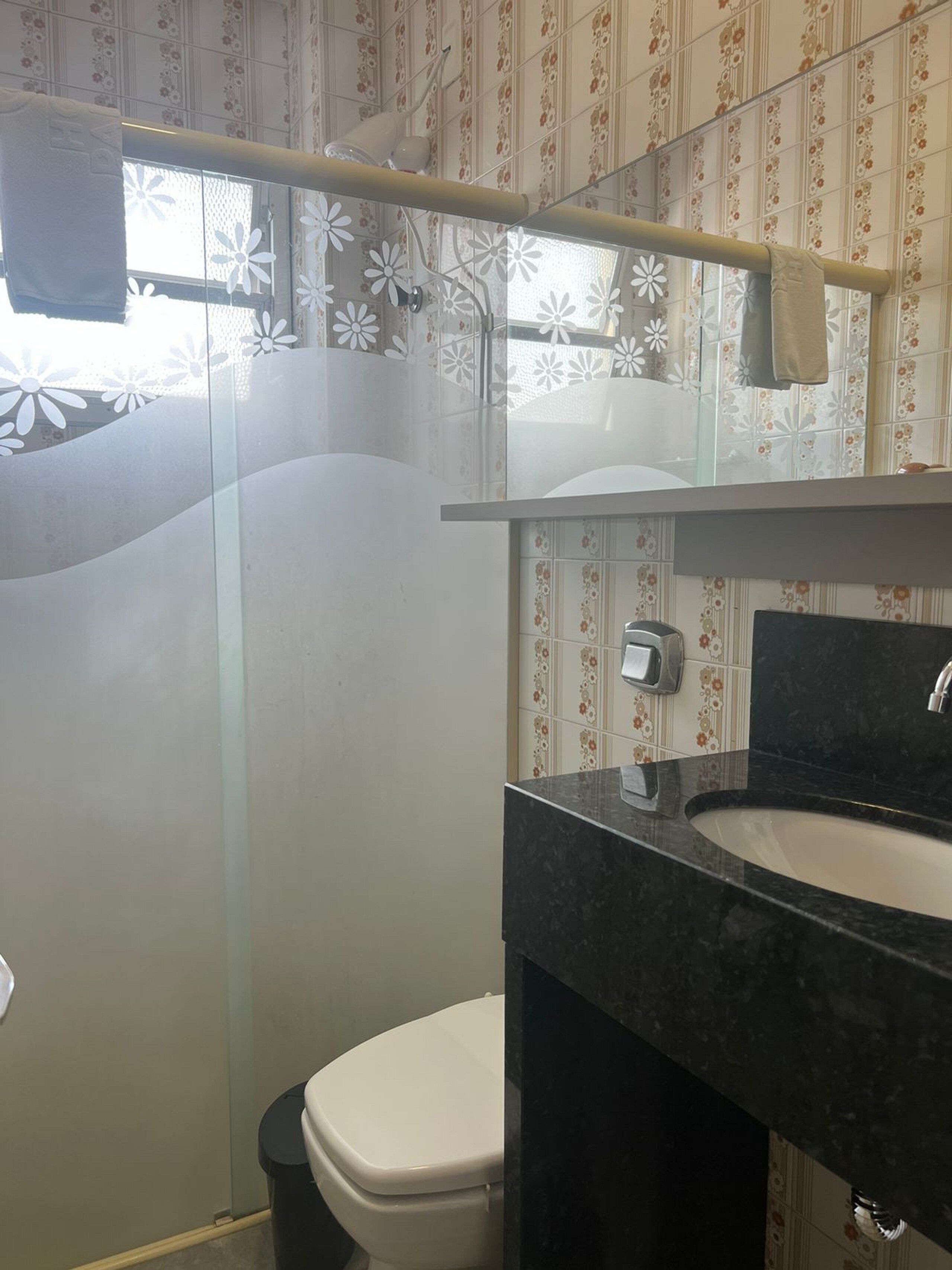 A bathroom with a toilet, a sink, and a shower area.