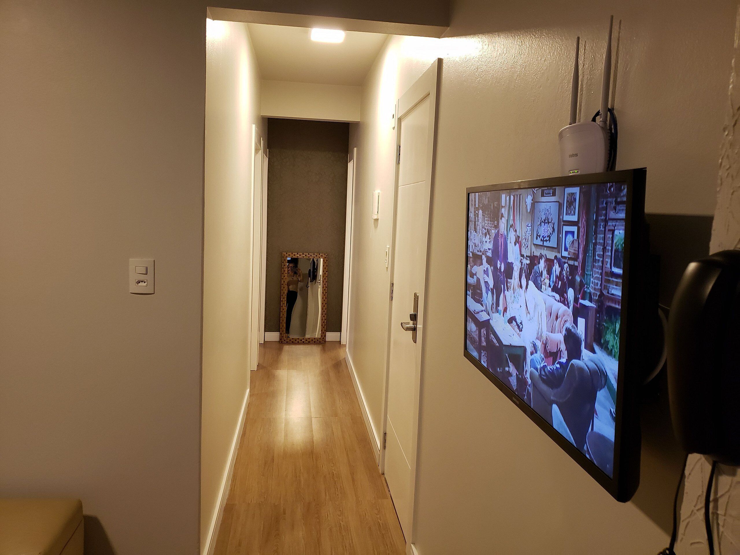 Egy folyosó, a falán egy televízió van, amely egy jelenetet vetít.