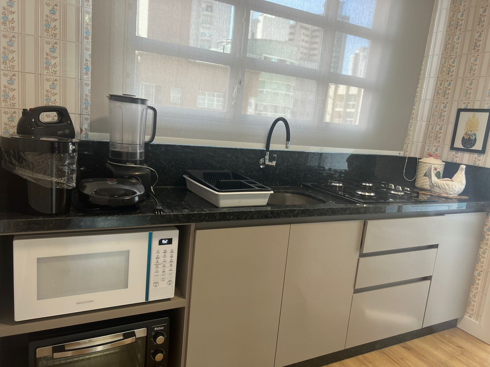 A kitchen with a coffee maker, blender, microwave, and gas stove.