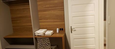 A bedroom with a wooden headboard, a desk with a chair, a white door, and two beds with beige covers.