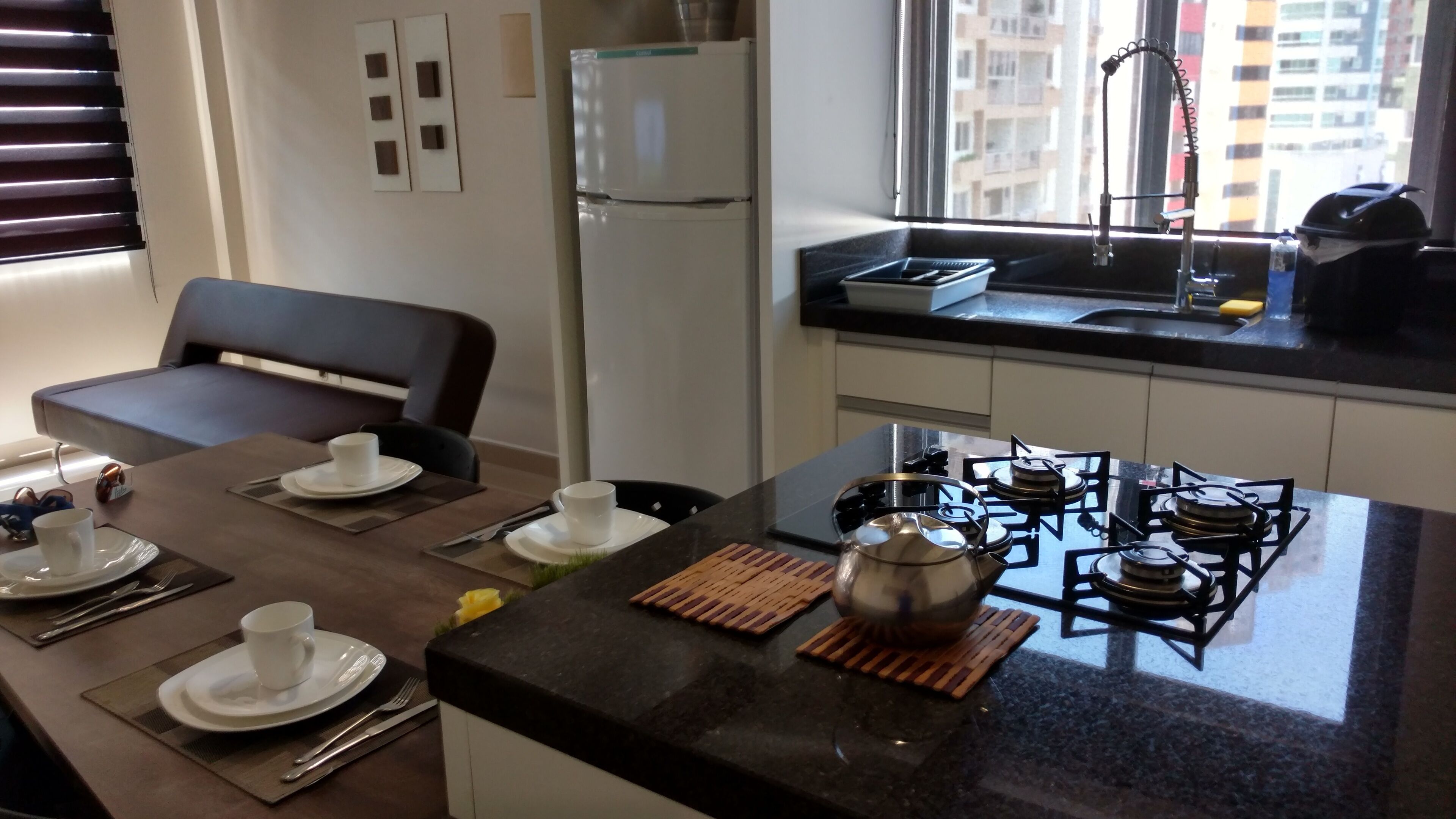 Una cocina moderna con estufa a gas, refrigerador y comedor con mesa para dos.