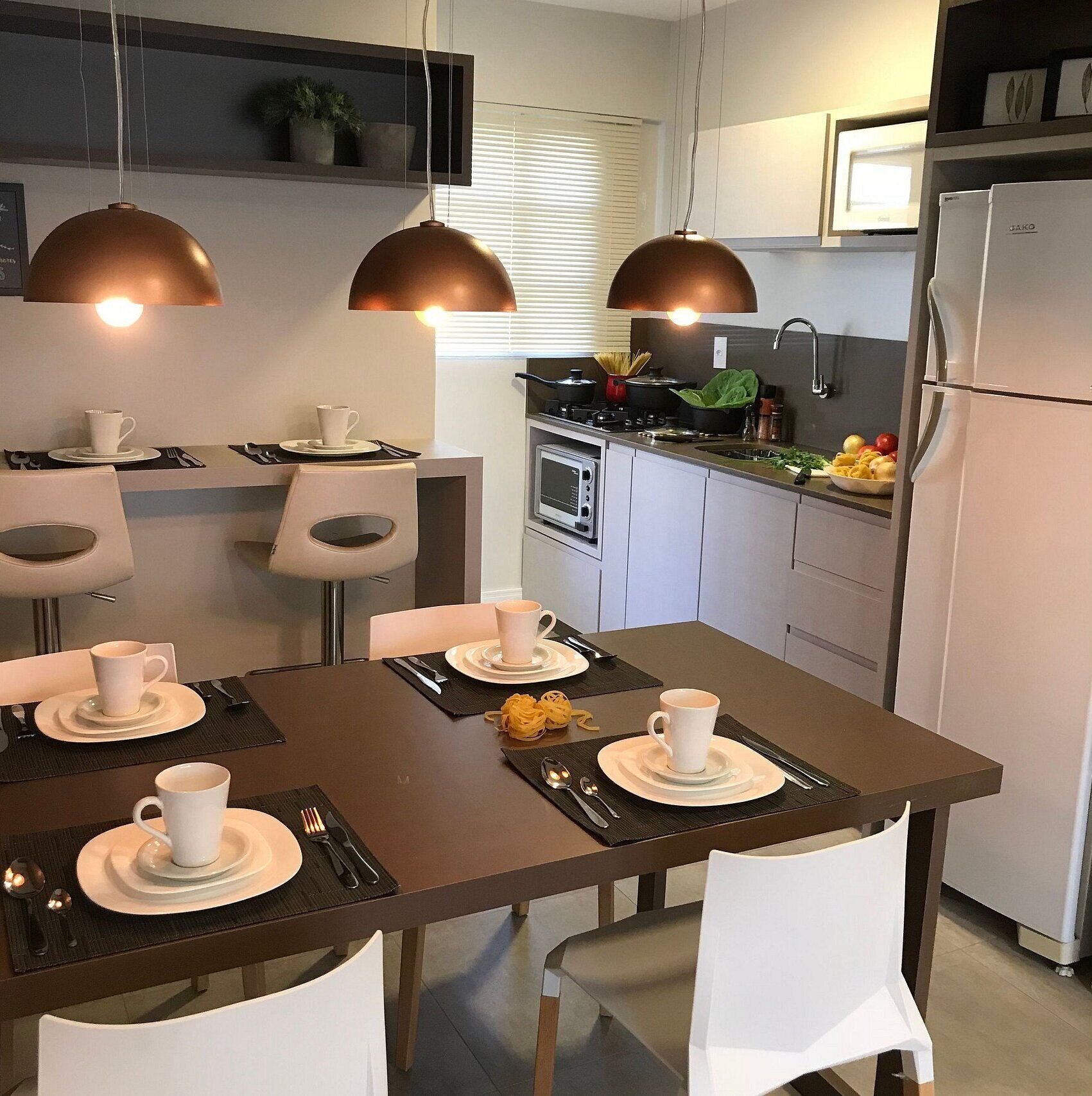 Eine moderne Küche mit Essbereich, ausgestattet mit Pendelleuchten, einem Kühlschrank und einem Herd.