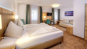 Una habitación de hotel con una cama grande, un sofá, un escritorio y un televisor.