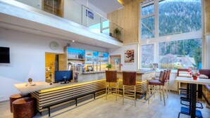 Un interior moderno con una zona de bar, asientos y ventanas amplias que ofrecen vistas al exterior.