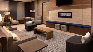 A modern living room with a flat-screen TV, a fireplace, and a seating area with sofas and a coffee table. - Residence Inn by Marriott Charlotte Northlake (Charlotte)