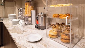 A kitchen area with a marble countertop, a coffee machine, and a display case with pastries. - Residence Inn by Marriott Charlotte Northlake (Charlotte)