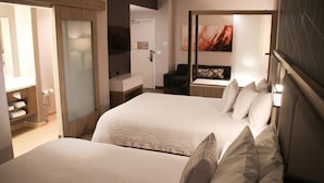 Una habitación de hotel con dos camas, baño y zona de estar.