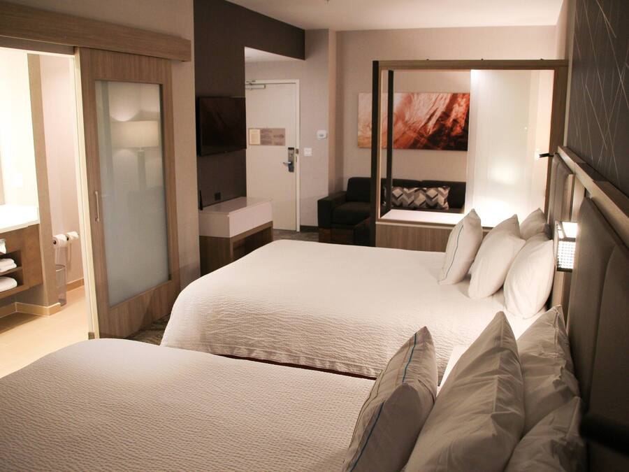A hotel room with two beds, a bathroom, and a seating area.
