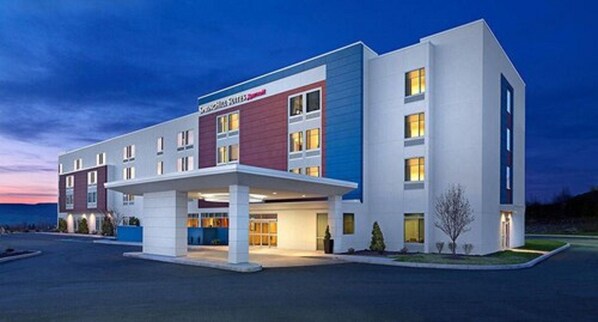 Un hotel moderno con techo plano, entrada cubierta y un cartel que indica que es un hotel Marriott.