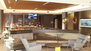 Un vestíbulo moderno con zona de bar, asientos y una pantalla de televisión.