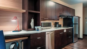 A modern kitchen with dark wood cabinets, stainless steel appliances, and a white countertop. - TownePlace Suites Toledo Oregon (Oregon)