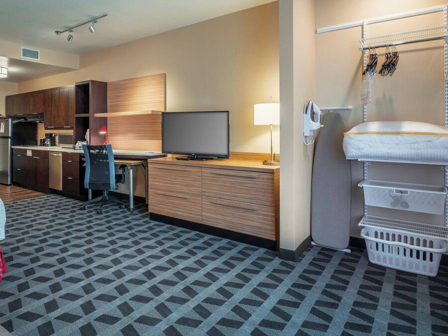 Une chambre d’hôtel équipée d’une kitchenette, d’une télévision, d’un bureau et d’un lit.