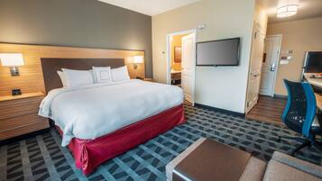 Een hotelkamer met een groot bed, een bureau, een televisie en een zichtbare badkamer door een geopende deur.